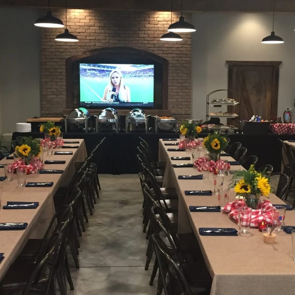 Gatlin's BBQ dining room set for an event with long tables, buffet, and TV on a brick wall.