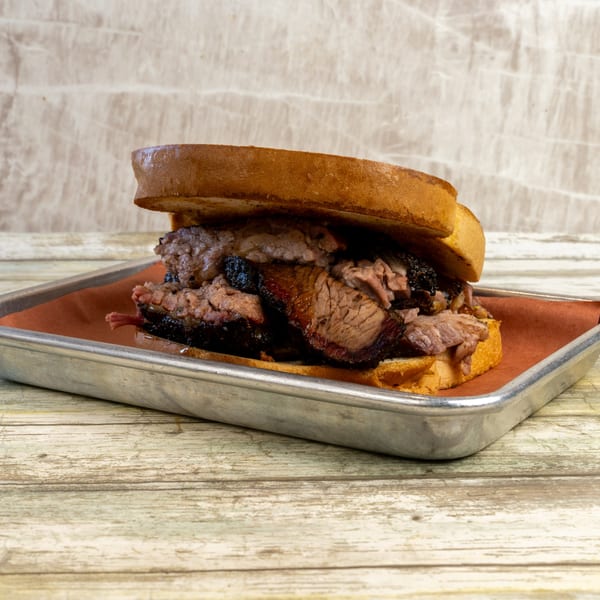 Gatlin's BBQ brisket sandwich on toasted bread, served on a metal tray with brown paper.