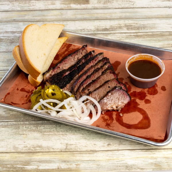 Gatlin's BBQ brisket plate with sliced meat, white bread, pickled jalapeños, onions, and BBQ sauce.