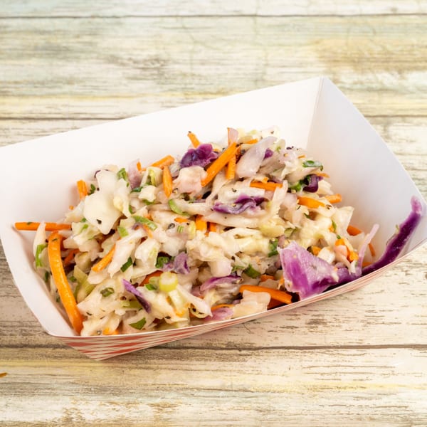 Gatlin's BBQ coleslaw in a paper tray, featuring shredded cabbage, carrots, and purple cabbage.