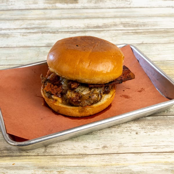 Gatlin's BBQ burger with bacon, melted cheese, and caramelized onions on a metal tray.