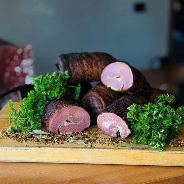 Smoked Gatlin's BBQ sausage, sliced open to show the pink meat, garnished with parsley and spices.